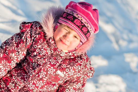Baby sits on snow, frowns and smile, portrait