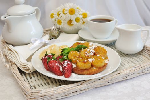 Breakfast with caramelized bananas and strawberries on a tray