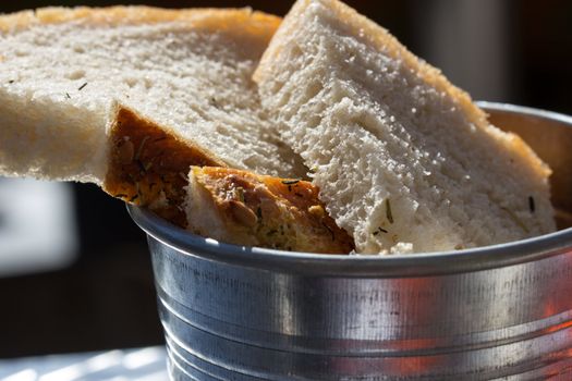 Picture of a few slices of olive bread in a metal bucket