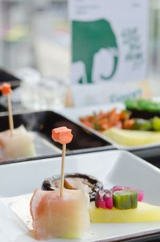 Salmon and fruit sticks with  melon , mixed pickled vegetable on plate , japanese style food