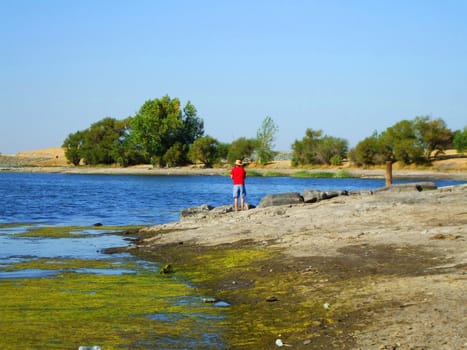 Fisherman fishing on a shore on a sunny day.