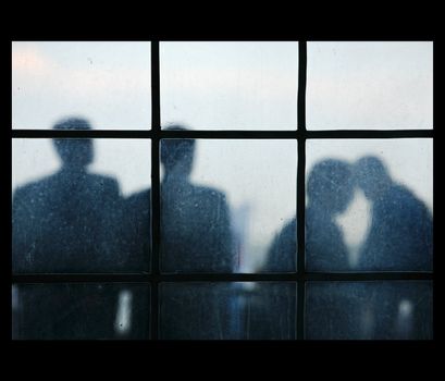 Four silhouettes of people behind of a window