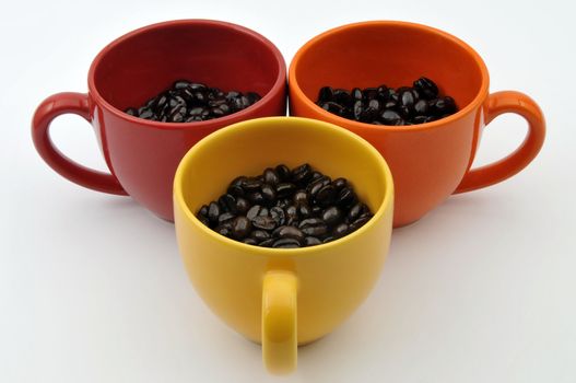 Three colorful cups full with coffe beans isolated on white