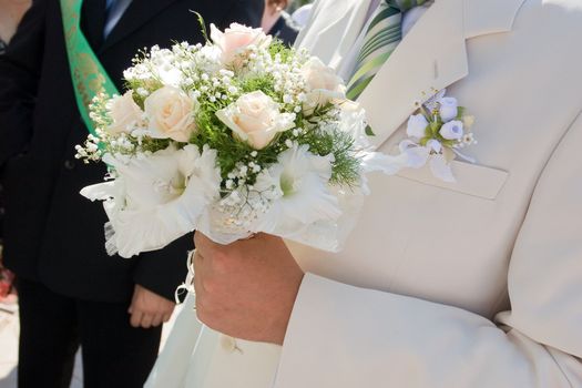 white rose bouquet in the hand of the groom
