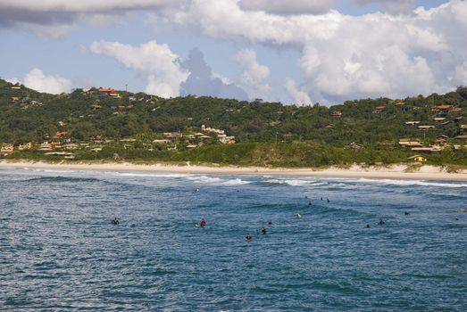 Wide angle shot of bay with several surfers in the water.