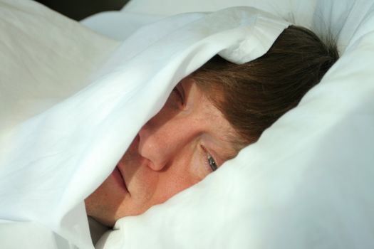 Man sleeping under white covers, ready to wake in the morning light