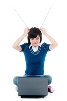 Portrait of an attractive young lady sitting on the floor with laptop and holding antennas on head over white background