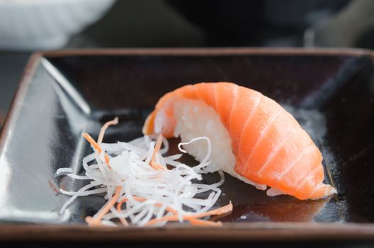 close up salmon sushi and slices daikon radishes