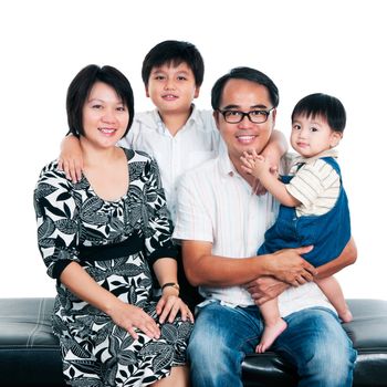 Portrait of a happy Asian family sitting together against white background.