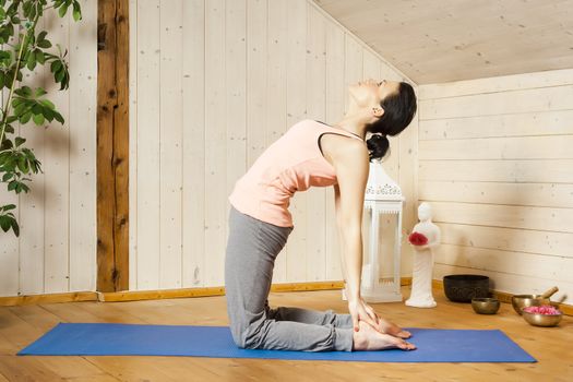 An image of a pretty woman doing yoga at home - Ushtrasana