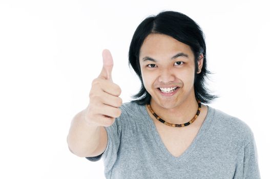 Portrait of a happy young Asian man giving thumb up gesture over whie background.