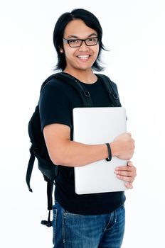 Portrait of a happy Asian student carrying laptop and backpack over white background.