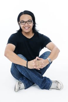 Happy young Asian man sitting relaxed on the  floor over white background.