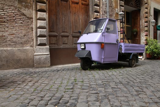 Rome, Italy. Cobblestone street and a funny three wheeled car.