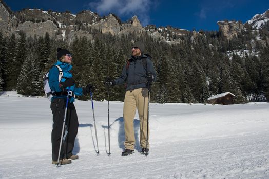 A couple  hiking on a snowy trail in val di fassa, in the dolomites