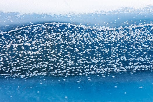 Fragment of frozen river surface. With the rapid decrease in air temperature river waterway covered with rime in the form of randomly placed snowflakes