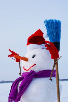 Lonely snowman with Santa's hat at a snowy field at winter time