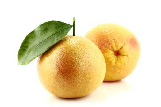 Ripe appetizing grapefruit with leaf on white background.