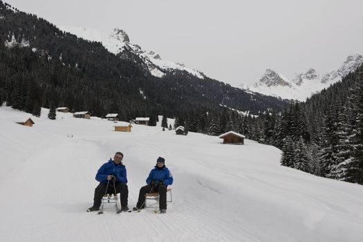 A  man and a boy on a sledge on a snowy trail in val di fassa, in the dolomites
