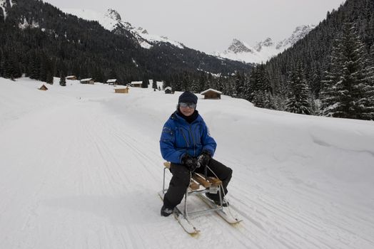 Young boy on a sledge on a snowy trail in val di fassa, in the dolomites