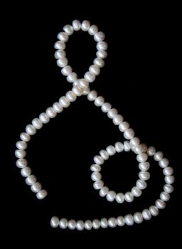 White pearls on the black velvet background 