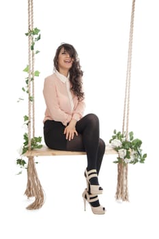 A woman in a pink blouse sitting on a swing isolated white background