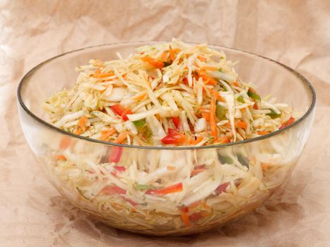 Coleslaw in glass bowl on brown crumpled recycled paper