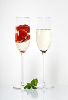 Two glasses of sparkling wine and strawberry on white