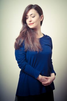 portrait of beautiful girl with long hair and blue sweater on gray background