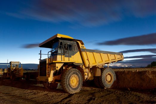 Huge auto-dump yellow mining truck night shot and excavator