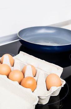 Eggs on induction stove. Frying pan in background