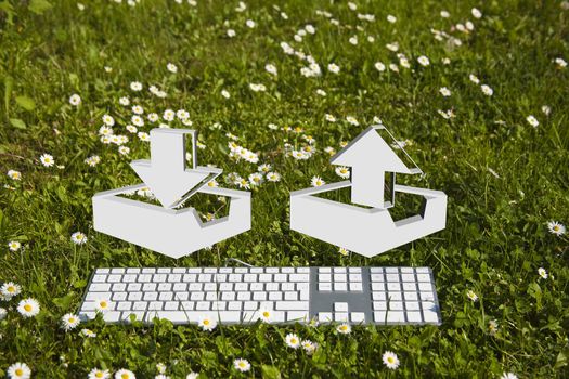 Downloading and uploading symbol and modern keyboard on green grass in garden