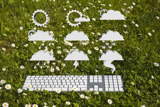 Forecast symbols and modern keyboard on green grass in garden