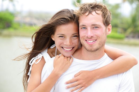 Young couple smiling happy portrait outdoors. Interracial couple in love together outside looking fresh and joyful at camera. Asian woman, Caucasian man.