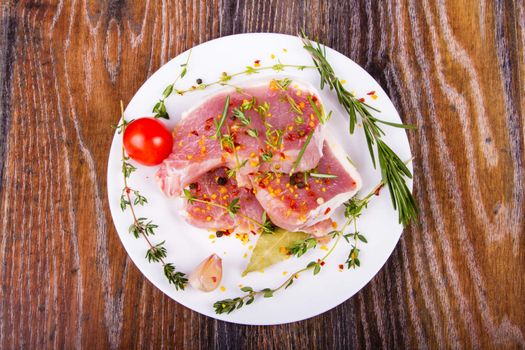 Raw fresh meat on a plate with condiments and fresh vegetables