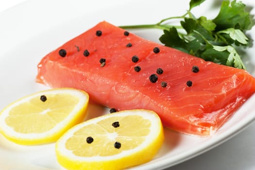 Closeup view of fresh salmon with parsley and lemon on a white plate