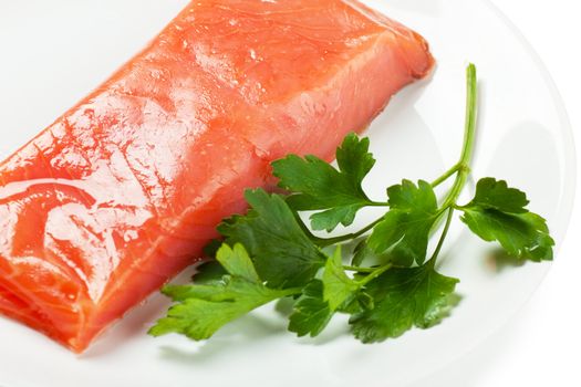Closeup view of fresh salmon with parsley on a white plate