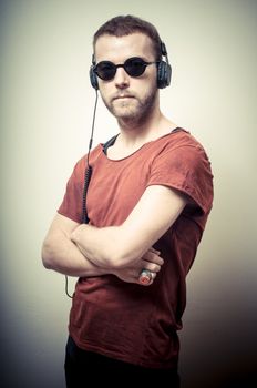 vintage portrait of fashion guy with headphones and sunglasses on gray background