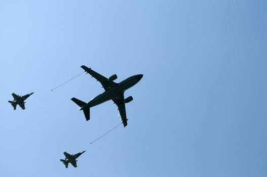 Two fighter jets moving closer to the fuel plane for in-flight fueling