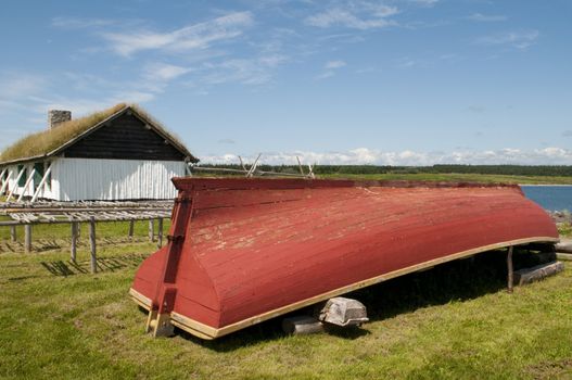 Vintage 18th century fishing boat with racks for drying fish and in the background the fisherman's home including a sod roof. 