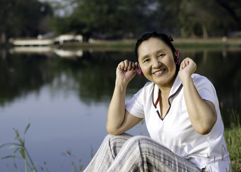 Beautiful asian woman listening music in headphones, outdoor portrait