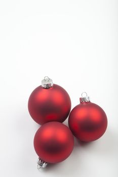 Red ball ornaments from Christmas trees on light grey paper.