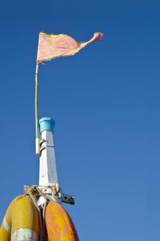 Dwarka Roadtrip. Concept of Rich blue sky split by a white mast bearing yellow life buoys and a pink frayed flag. Generic shot location Bet Dwarka, Gujarat, India