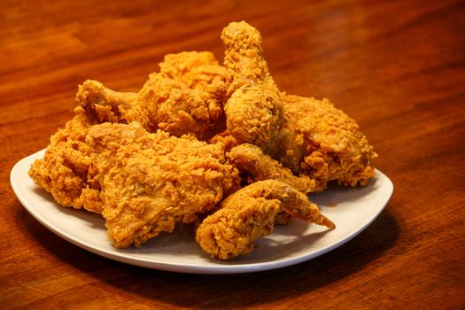 Fresh, fried chicken on a square white plate on a wood table