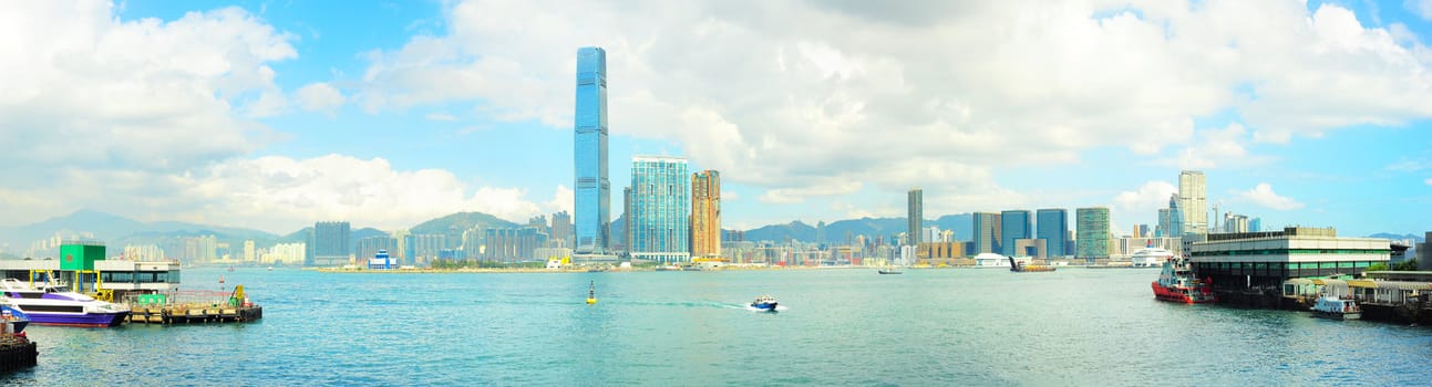 View from Hong Kong to Kowloon island in the sunshine day. Ferry piers on both side of picture.