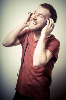vintage portrait of fashion smiling guy with headphones on gray background