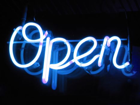 A neon "open" sign glowing blue in the window of a restaurant.