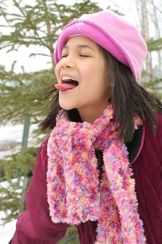 Nine year old girl sticking out her tongue trying to catch a snowflake