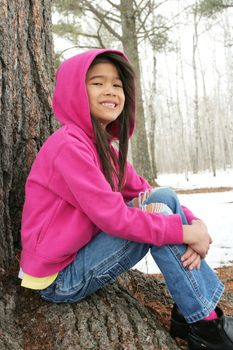 Child sitting under tree in winter