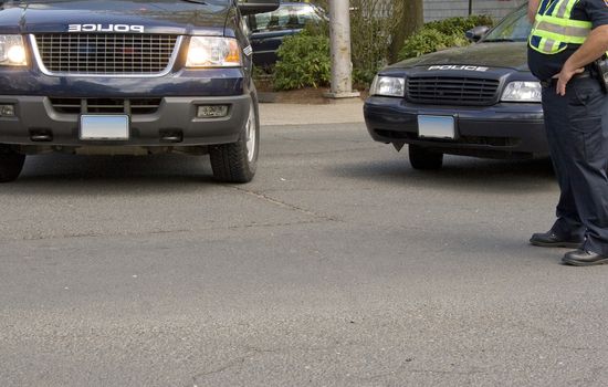 A police background with two vehicles and an officer at work.  Plenty of copy space in the street.